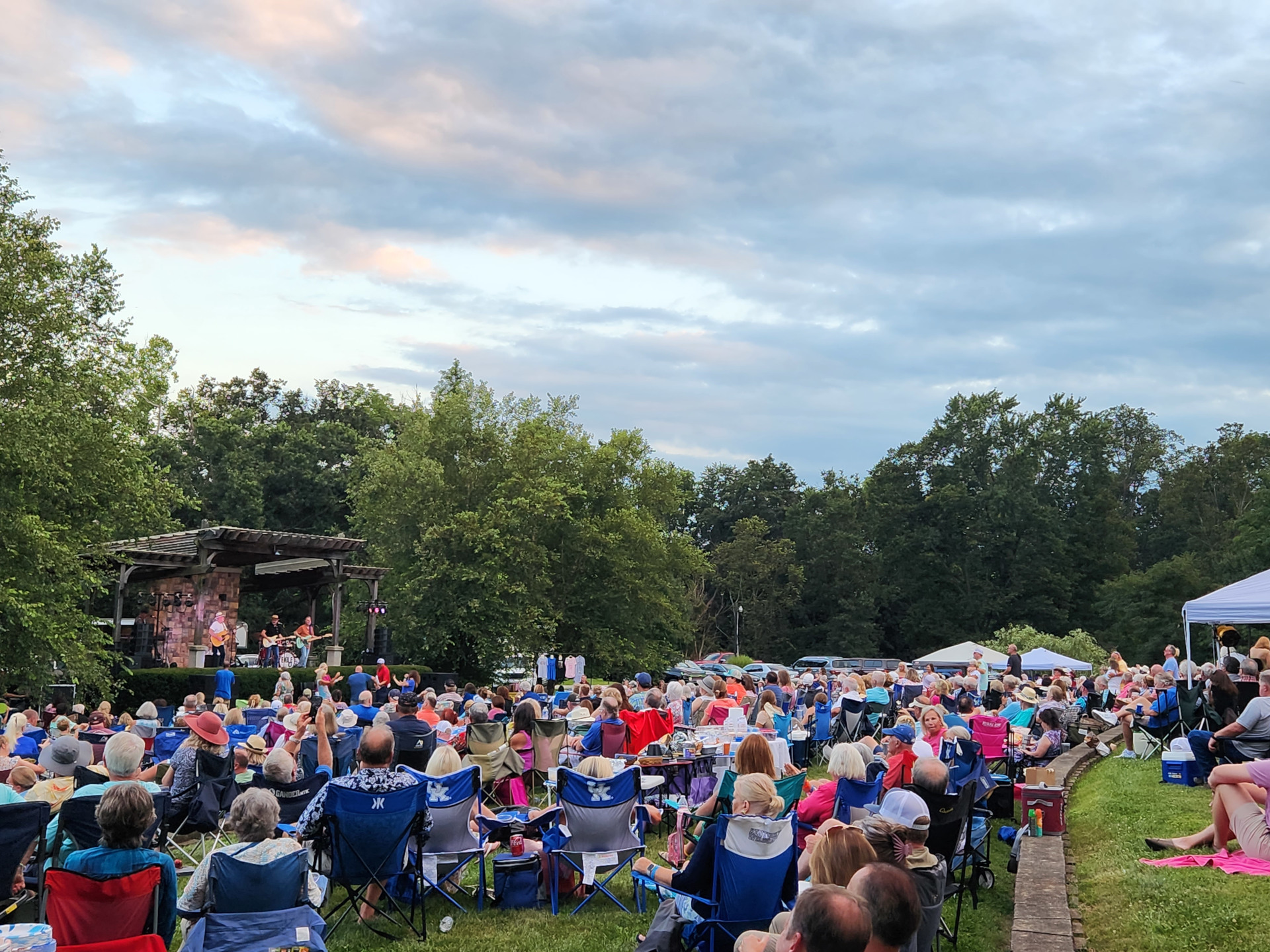 A large crowd of people seated in lawn chairs enjoying an outdoor concert