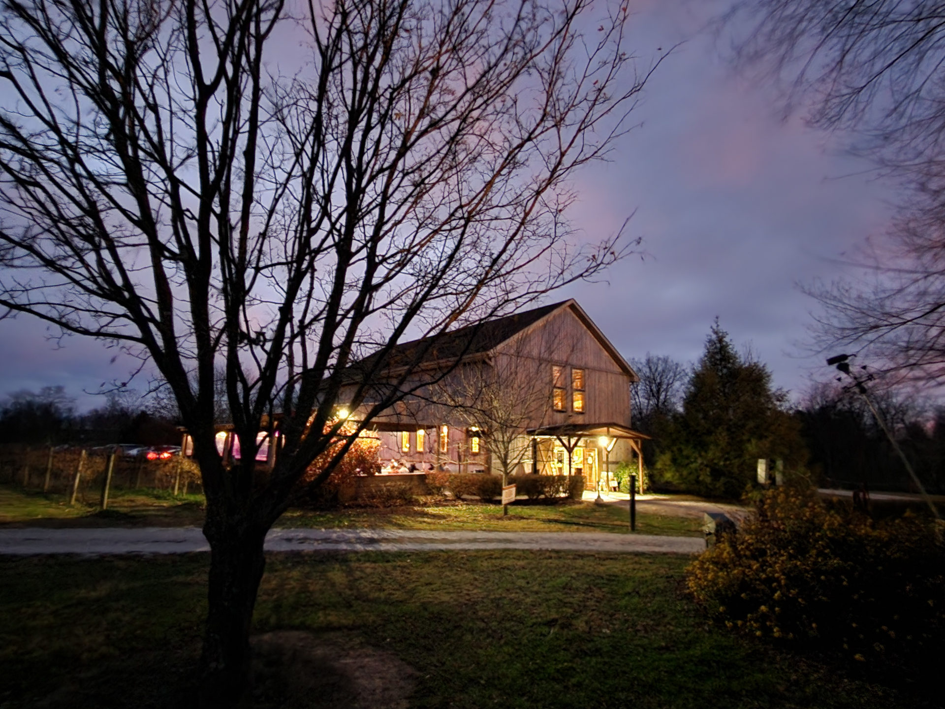 A dusky scene featuring a barn and a tree in the foreground,